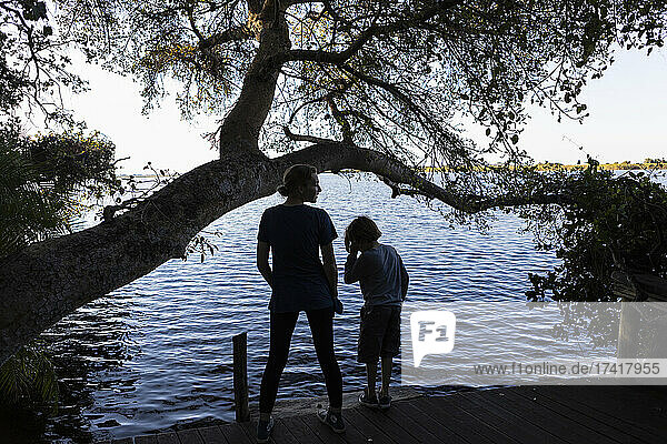 Zwei Kinder am Rande einer Wasserstraße  Rückansicht  Okavango-Delta