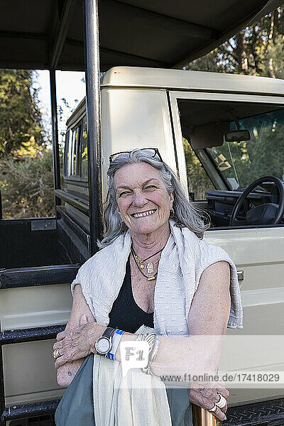 Senior woman smiling standing by a safari jeep in Botswana.