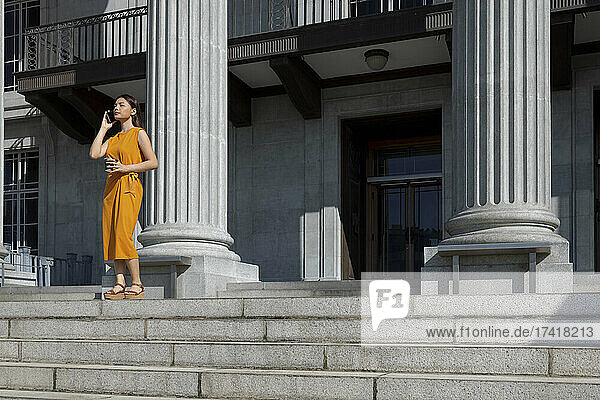 Junge Frau telefoniert  während sie in der Nähe der Säule der National Gallery in Singapur steht