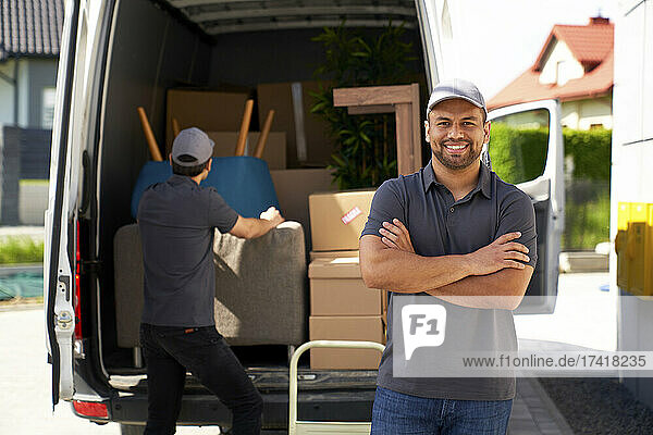 Smiling male delivery person standing near van