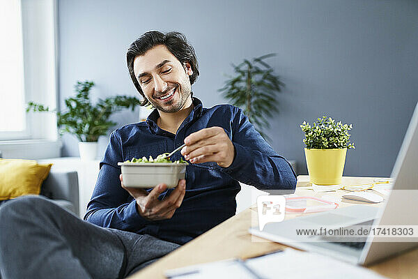 Male professional eating food during break at home office