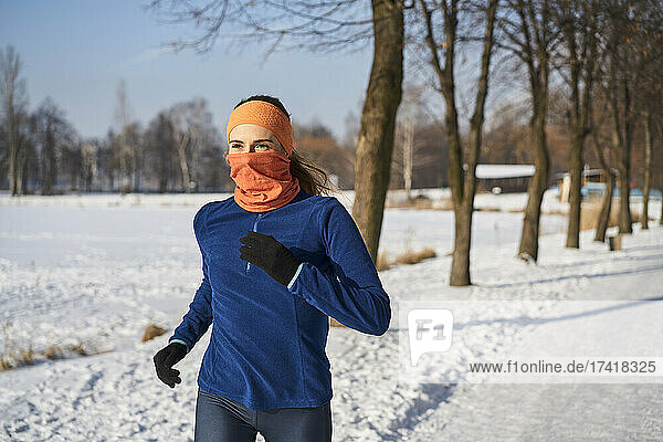 Woman wearing gaiter face mask while running during winter