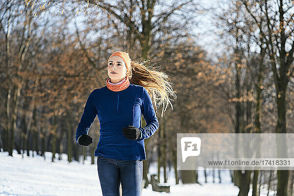 Young woman looking away while running during winter