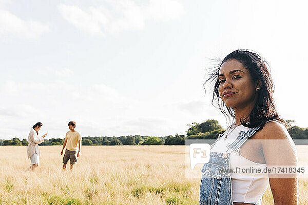 Smiling woman standing at meadow with friends in background