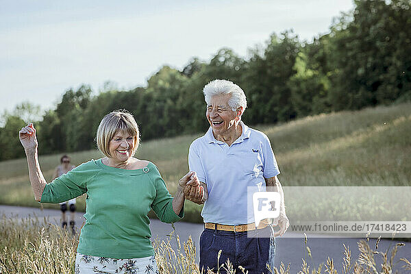 Cheerful senior couple holding hands while walking together