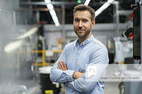 Businessman with arms crossed standing at industry