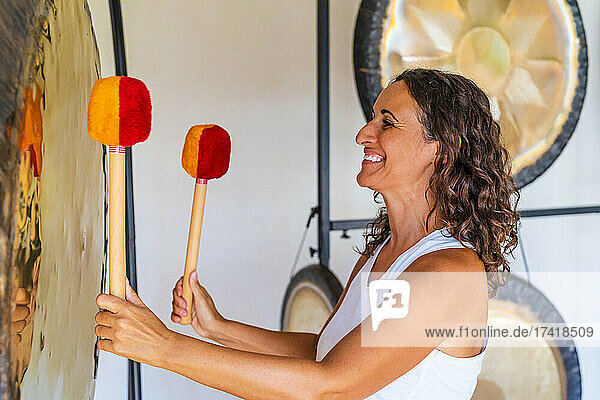 Smiling female therapist playing percussion musical instrument at studio