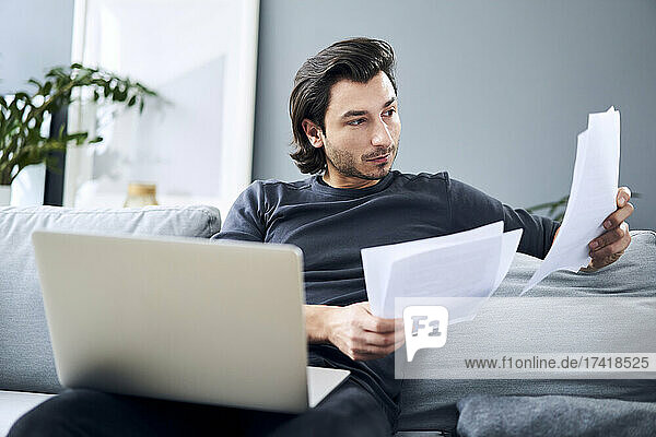 Male professional looking at documents while sitting at home