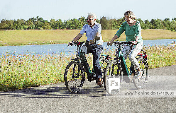 Senior couple riding bicycle on road
