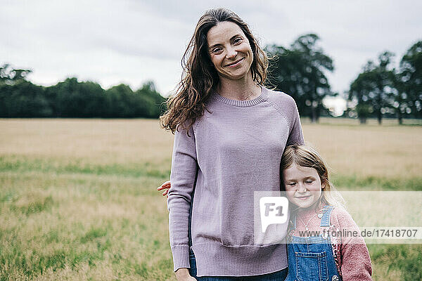 Smiling mother standing with daughter at meadow
