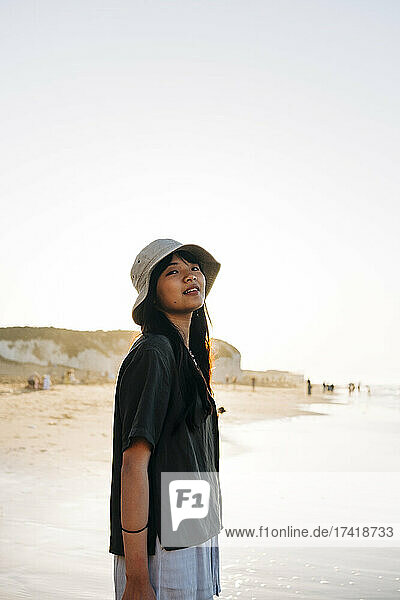 Young woman day dreaming while standing at beach