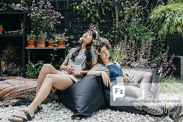 Freunde entspannen sich mit einer Kaffeetasse auf einem Sitzsack im Hinterhof