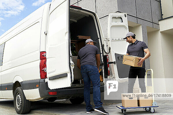 Delivery men loading cardboard box in van