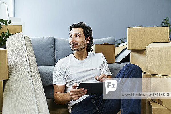 Man looking away holding graphic tablet at home