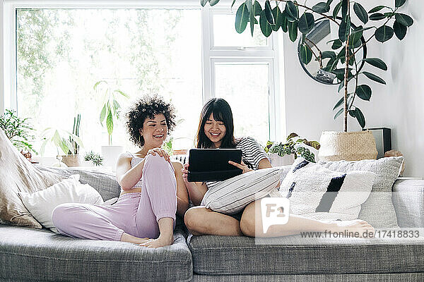 Young women using digital tablet while sitting on sofa