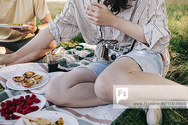 Friends having food while sitting on picnic blanket