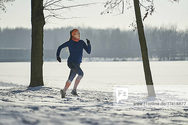 Woman running on snow during winter
