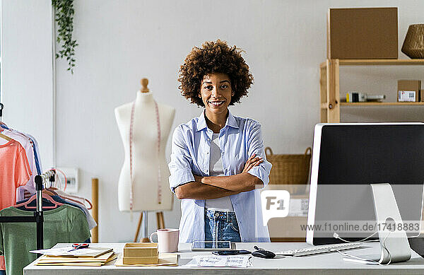 Young female entrepreneur standing with arms crossed at studio
