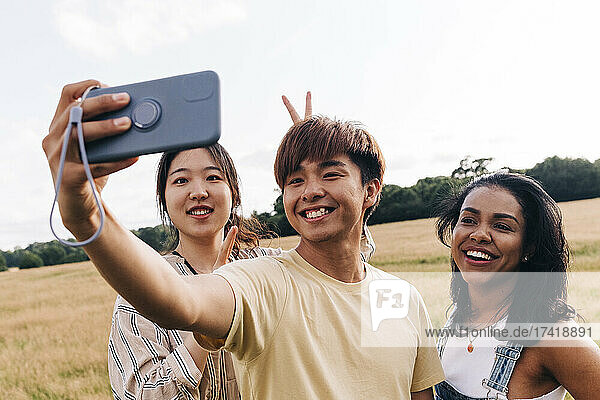 Lächelnde Freunde  die im Park ein Selfie mit dem Handy machen