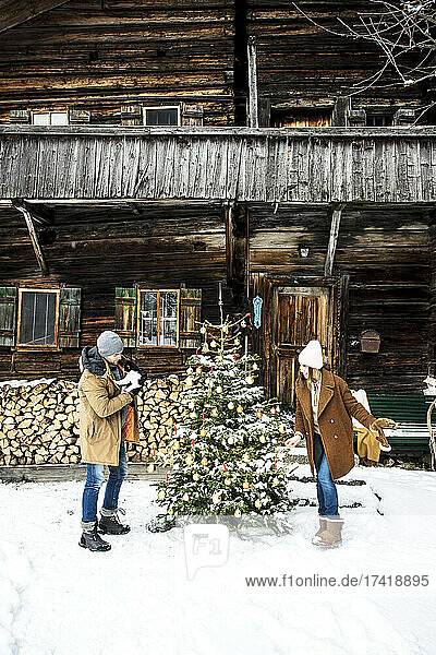 Paar schmückt den Weihnachtsbaum  während es im Schnee steht