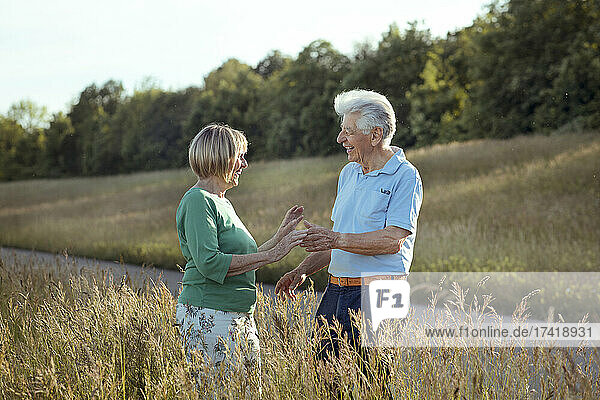 Cheerful couple looking at each other while standing on meadow