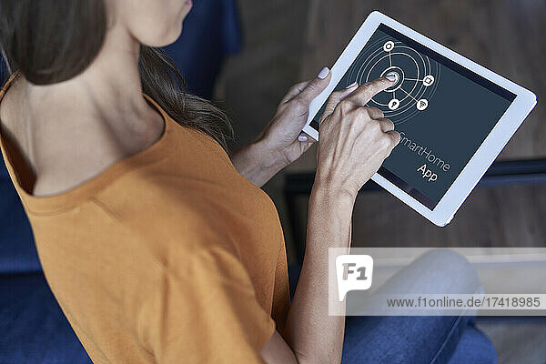 Frau nutzt Smart-Home-Anwendung auf digitalem Tablet zu Hause
