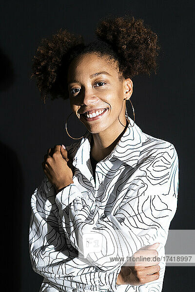 Afro woman smiling against black background