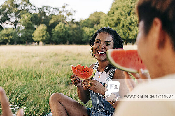 Smiling friends eating watermelon during picnic at park