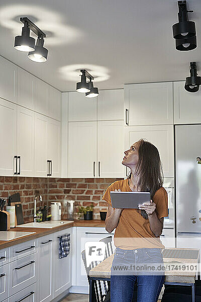 Woman controlling lights through digital tablet at home