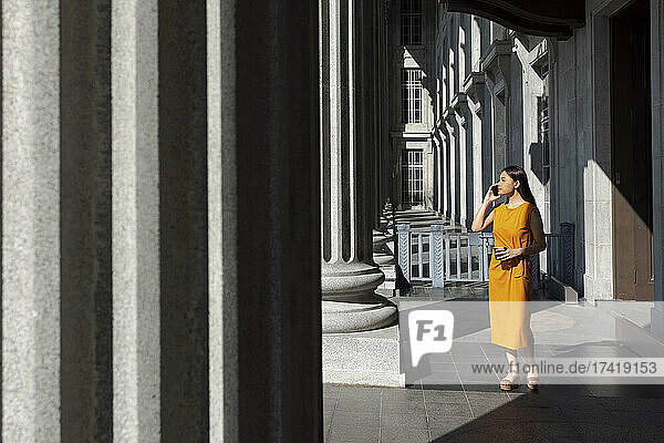 Frau spricht mit ihrem Smartphone  während sie in der Nähe der Säule der National Gallery in Singapur steht