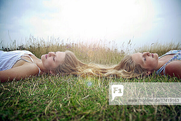 Female friends lying with eyes closed on grass