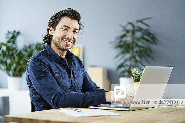 Male freelance worker with laptop on desk at home office