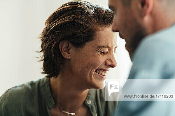 Happy woman with eyes closed laughing near man