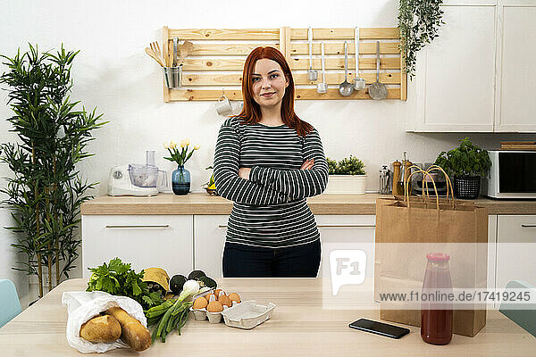 Redhead woman standing with arms crossed in kitchen