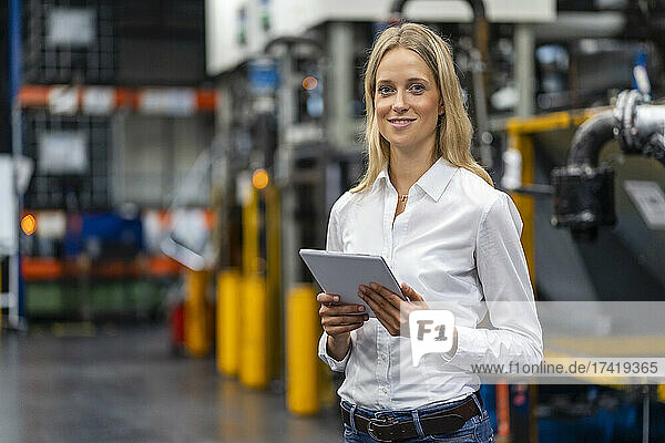 Female professional with digital tablet standing at factory
