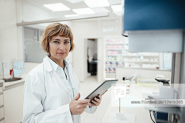 Female professional holding digital tablet while standing at laboratory