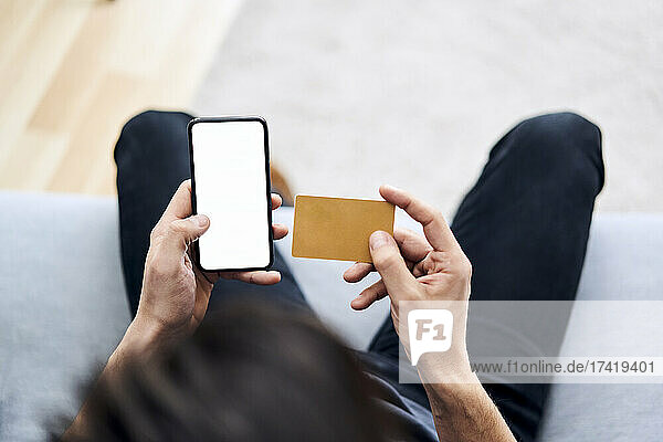 Mann  der online mit Kreditkarte und Smartphone bezahlt