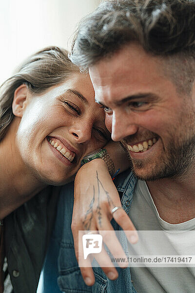 Happy woman leaning on boyfriend shoulder at home