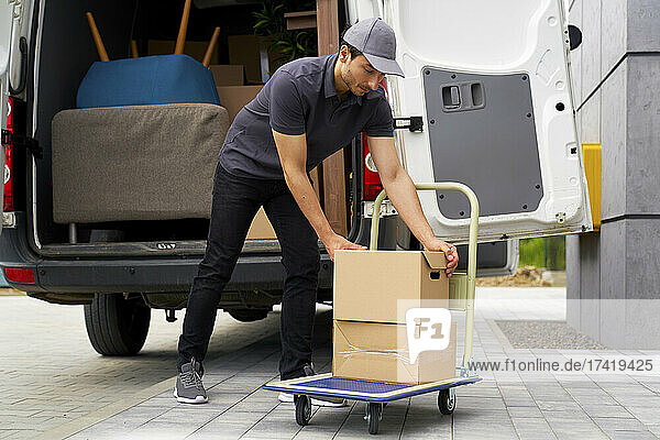 Male delivery person unloading boxes from moving van