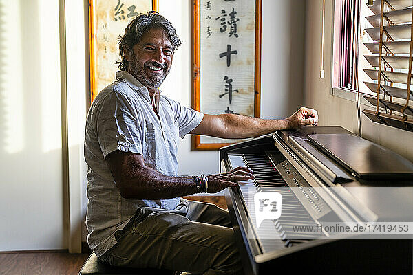 Lächelnder Mann  der zu Hause Klavier spielt