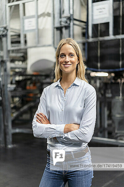 Smiling businesswoman with arms crossed at factory