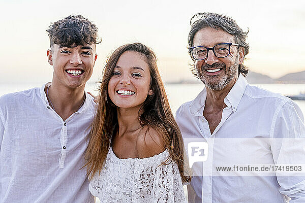 Beautiful woman standing with father and brother at beach