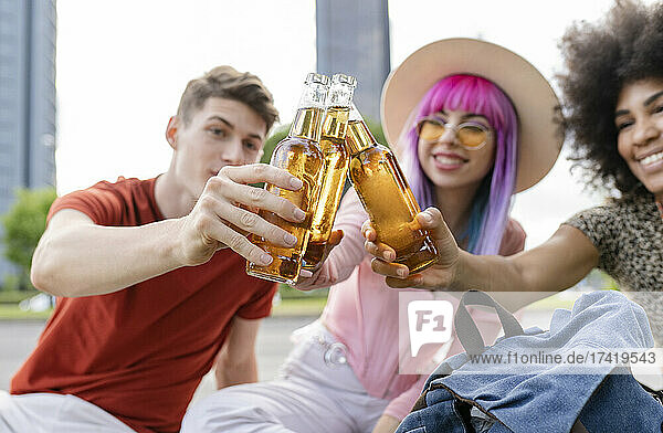 Multi-ethnic male and female friends toasting drinks at park