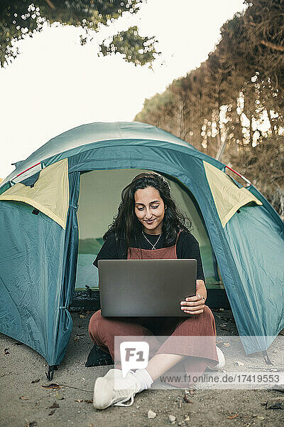 Junge Frau arbeitet am Wochenende im Zelt am Laptop