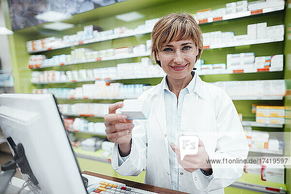 Female pharmacist with medicine gesturing at medical store