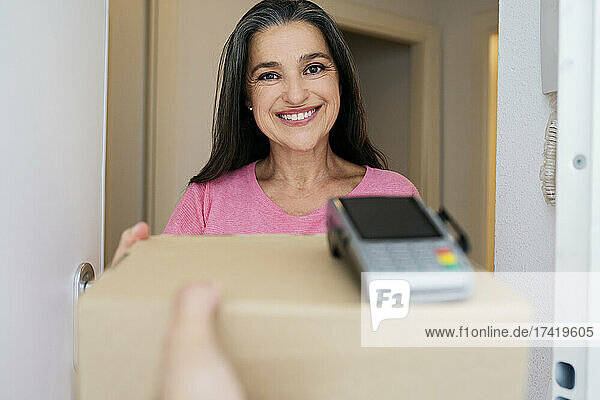 Lächelnde Frau erhält Paket vom Zusteller