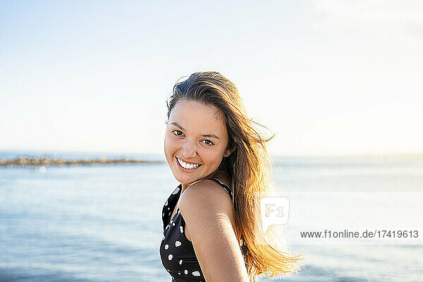 Beautiful woman with brown hair smiling at beach