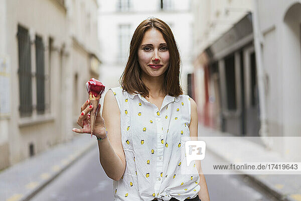 Young woman with ice cream standing on street