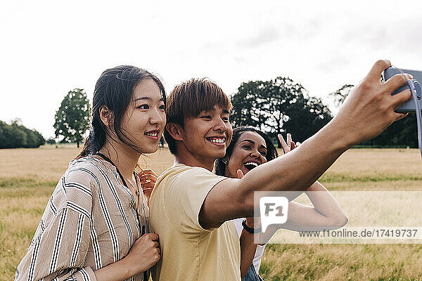 Happy friends taking selfie through smart phone at park