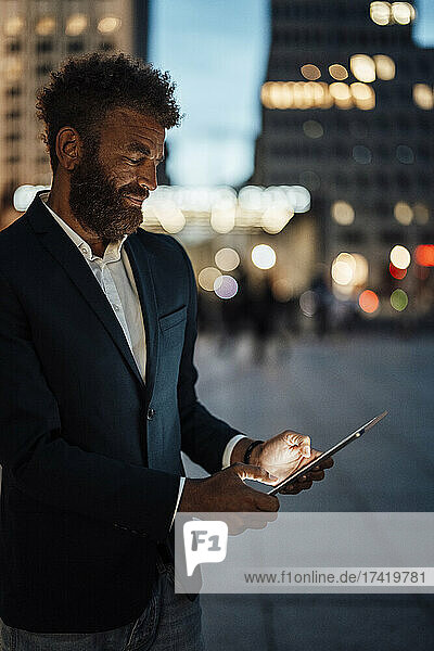 Bärtiger Geschäftsmann  der nachts am digitalen Tablet arbeitet